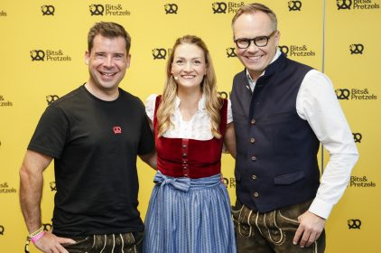 Gruppenfoto von Felix Haas, Digitalministerin Gerlach und Bernd Storm vor der gelben Pressewand der Bits & Pretzels 2023.